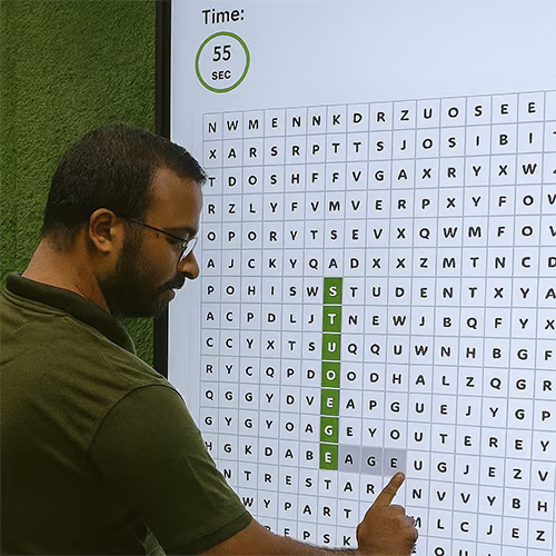 Guest playing interactive word search game at corporate event in Dubai, with branded screen, vibrant green backdrop
