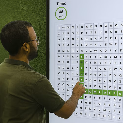 Guest playing interactive word search game at corporate event in Dubai, with branded screen, vibrant green backdrop