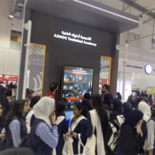 Students and guests play the Plinko Trivia Challenge at the ADNOC Technical Academy booth during a busy Dubai event