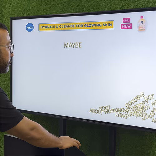 Arab woman using Sayit AI at a Dubai corporate event, speaking into a mic as 3D branded text appears on a large screen, showcasing interactive event technology rental