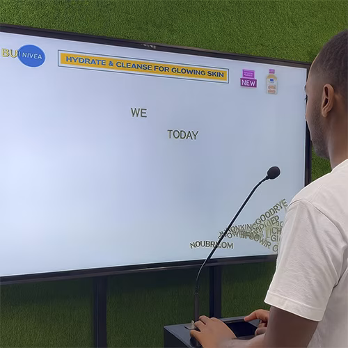 Arab woman using Sayit AI at a Dubai corporate event, speaking into a mic as 3D branded text appears on a large screen, showcasing interactive event technology rental