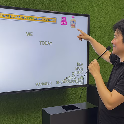 Arab woman using Sayit AI at a Dubai corporate event, speaking into a mic as 3D branded text appears on a large screen, showcasing interactive event technology rental
