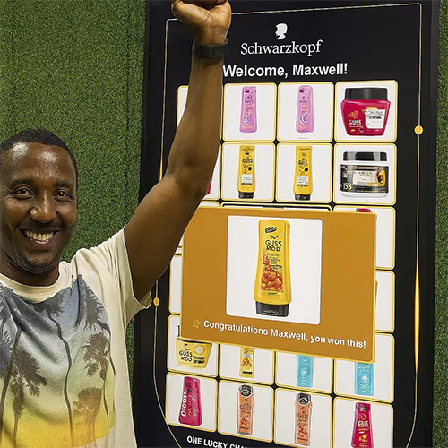 Guest playing Scan & Win interactive game by scanning QR code at a mall activation event in Dubai, with live name display and prize reveal on a big screen.