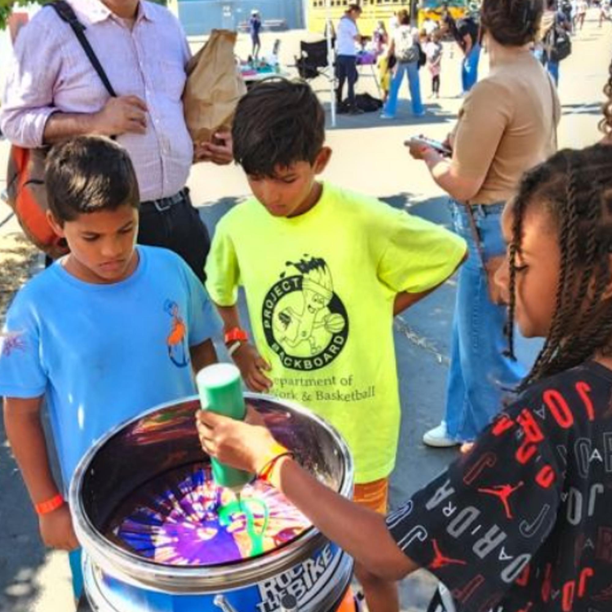 Guest pedaling the Spin Art Bike to create colorful artwork at an event, with vibrant paints splashing onto the spinning canvas.