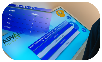 Touchscreen showing quiz results and a Dubai tower trivia question, with answer options and a person in a dark shirt standing beside the screen